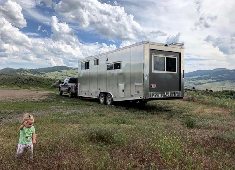 a child playing in front of a travel trailer that is off road
