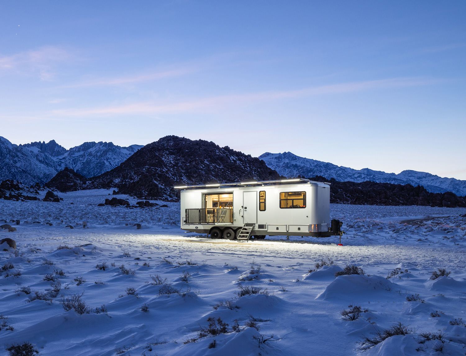 A Living Vehicle at camp in the snow below the mountains