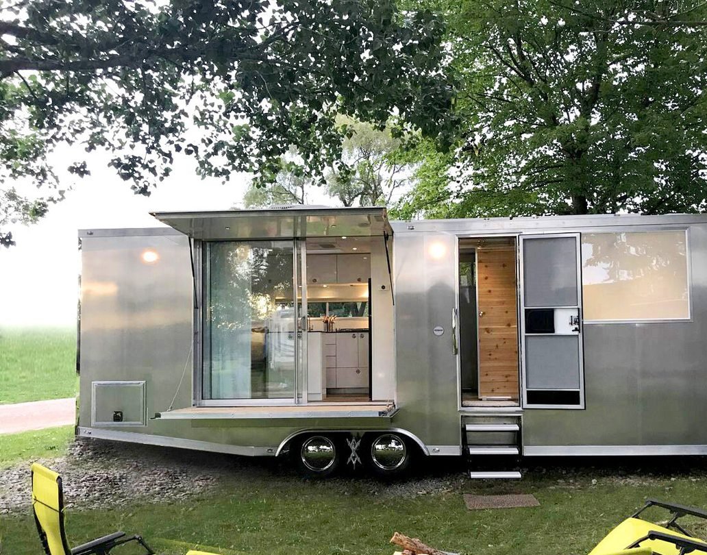A first-generation all-aluminum Living Vehicle travel trailer on a lawn