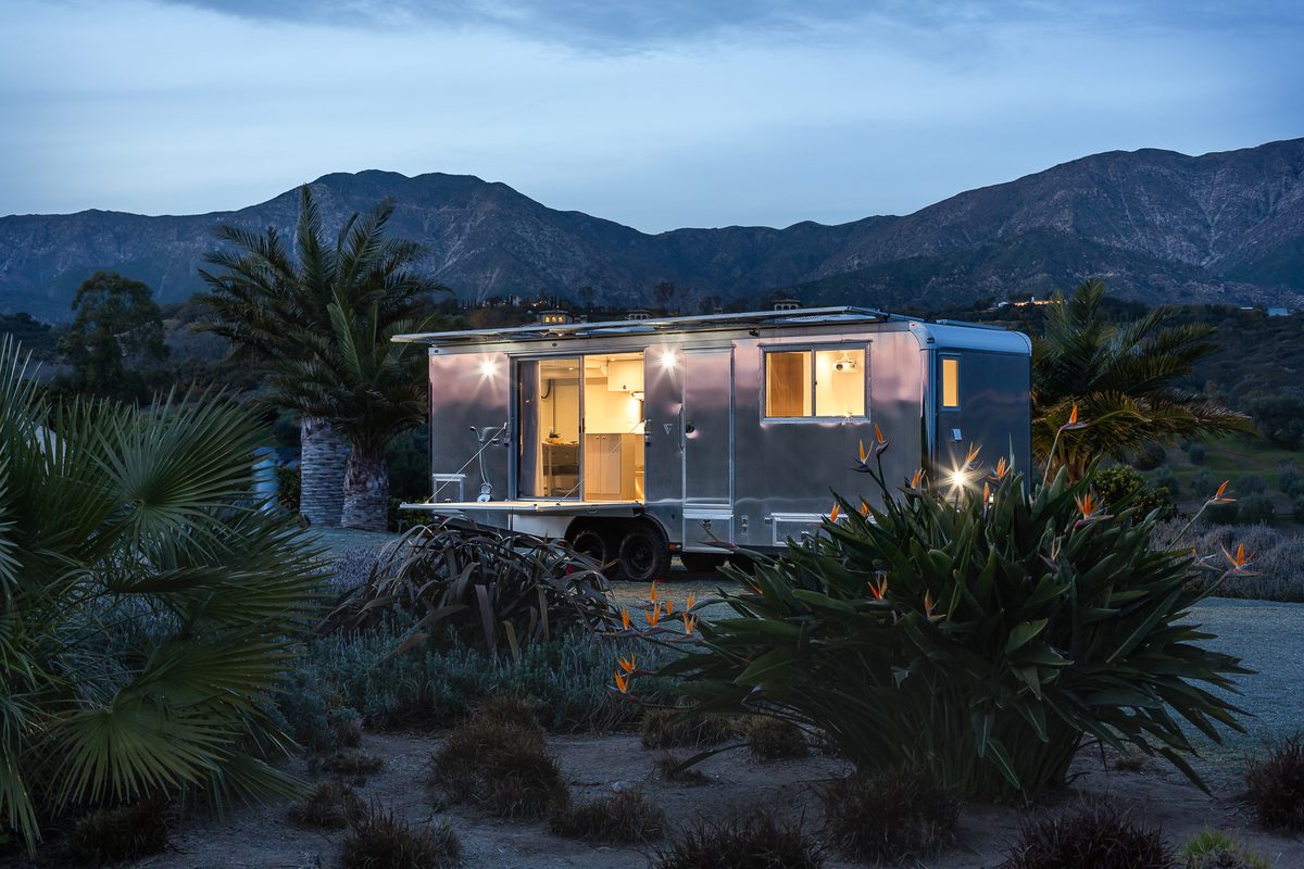 A first-generation Living Vehicle at twilight among palms below the mountains