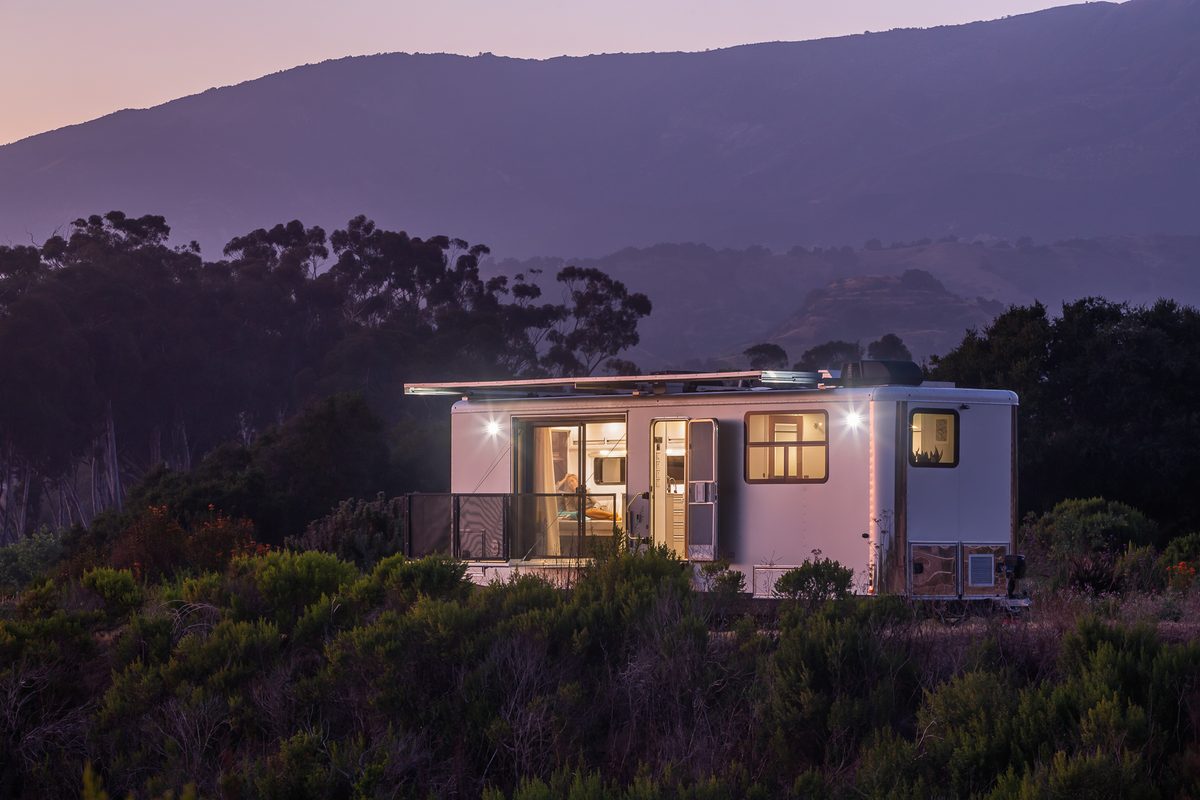 A Living Vehicle travel trailer at dusk on the coast