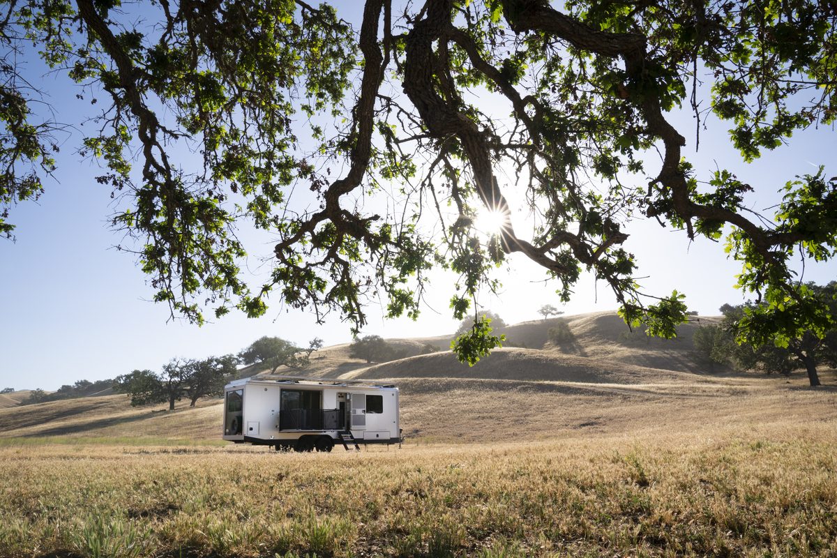 A Living Vehicle HD29 travel trailer under an oak in an open field