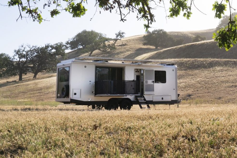 A Living Vehicle HD29 travel trailer in an open field of golden grass