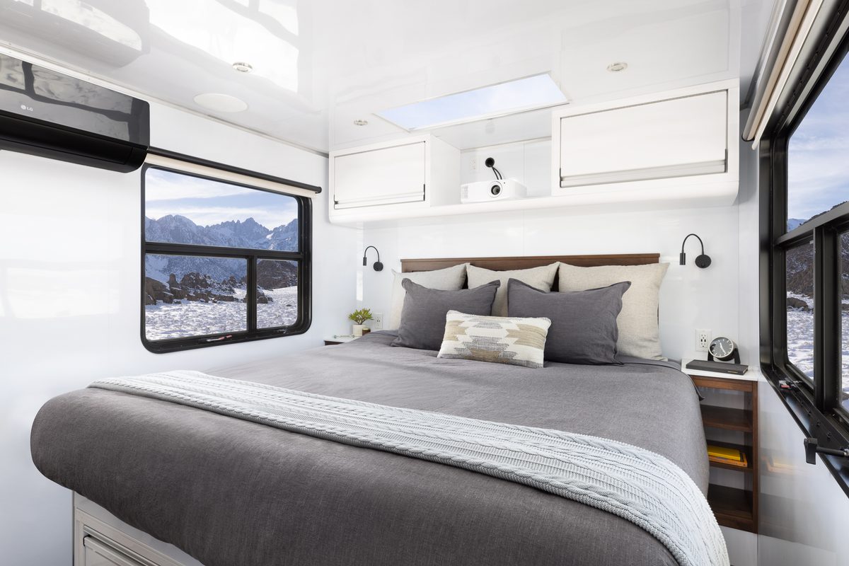 The bedroom of a Living Vehicle with a snowy view through the window