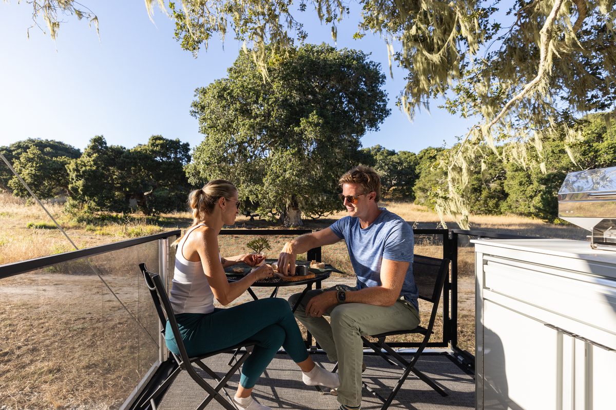 A couple eating dinner on the deck of a Living Vehicle