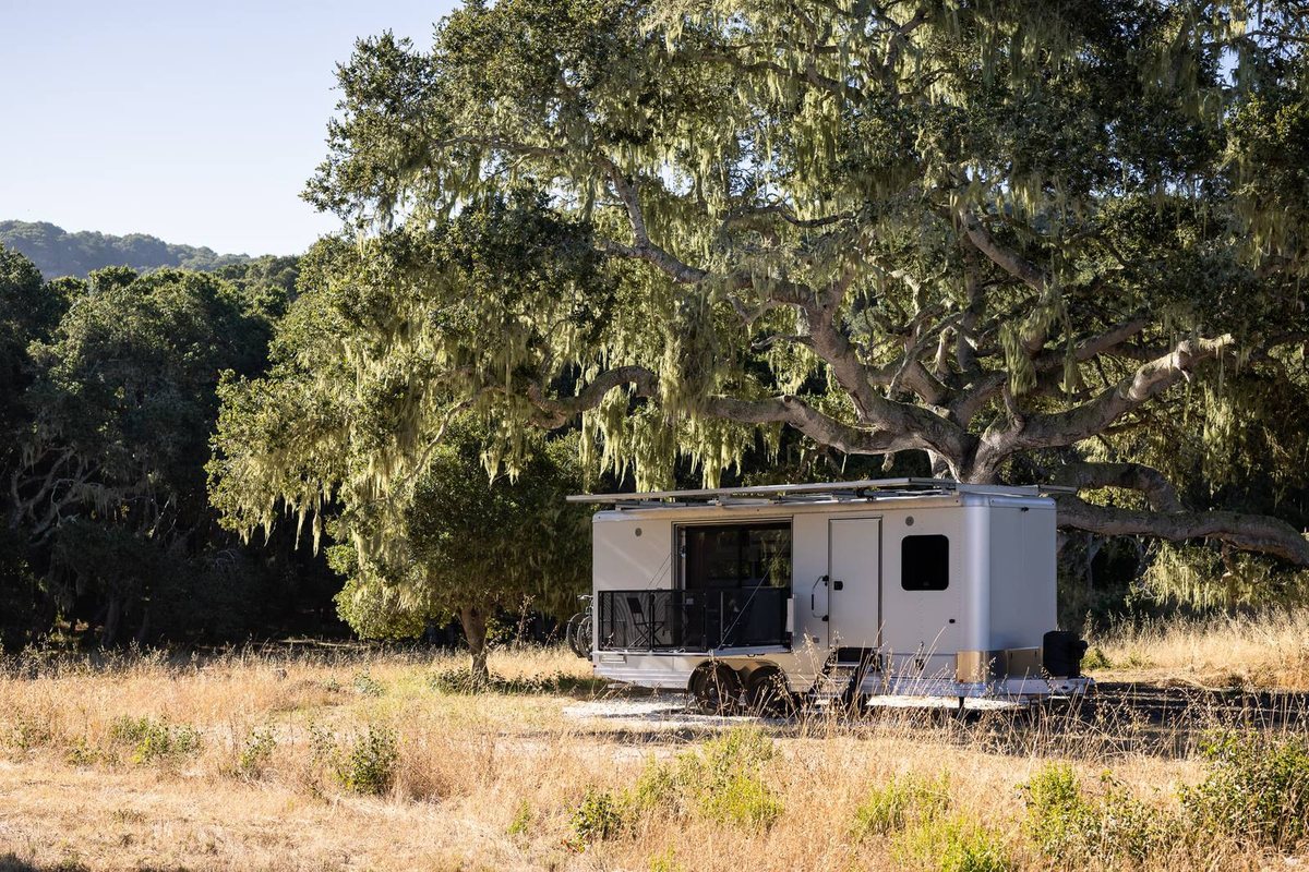 A Living Vehicle HD24 with its deck open under a large oak tree